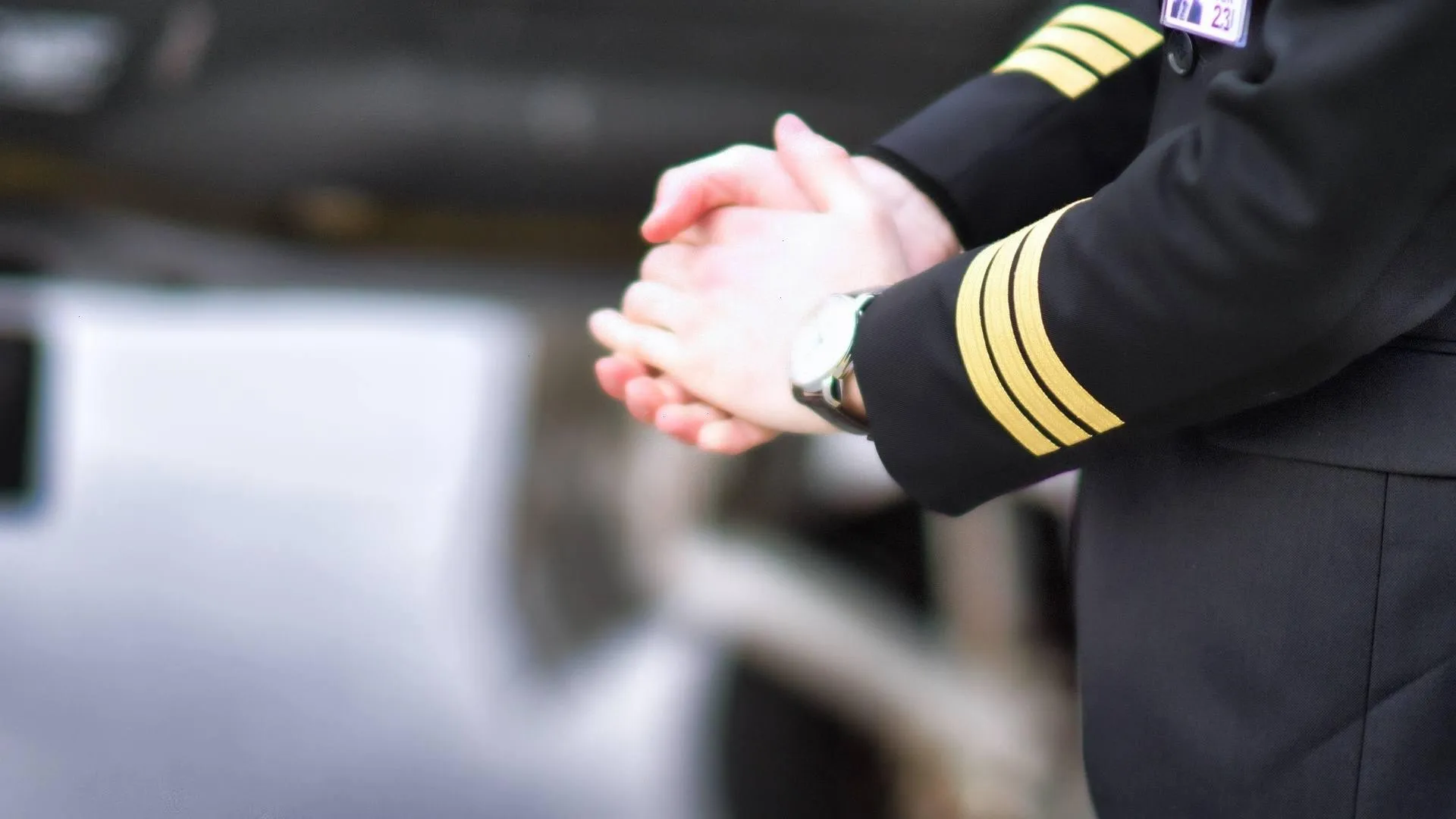 Gefaltete Hände eines Piloten, Uniformärmel mit Streifen