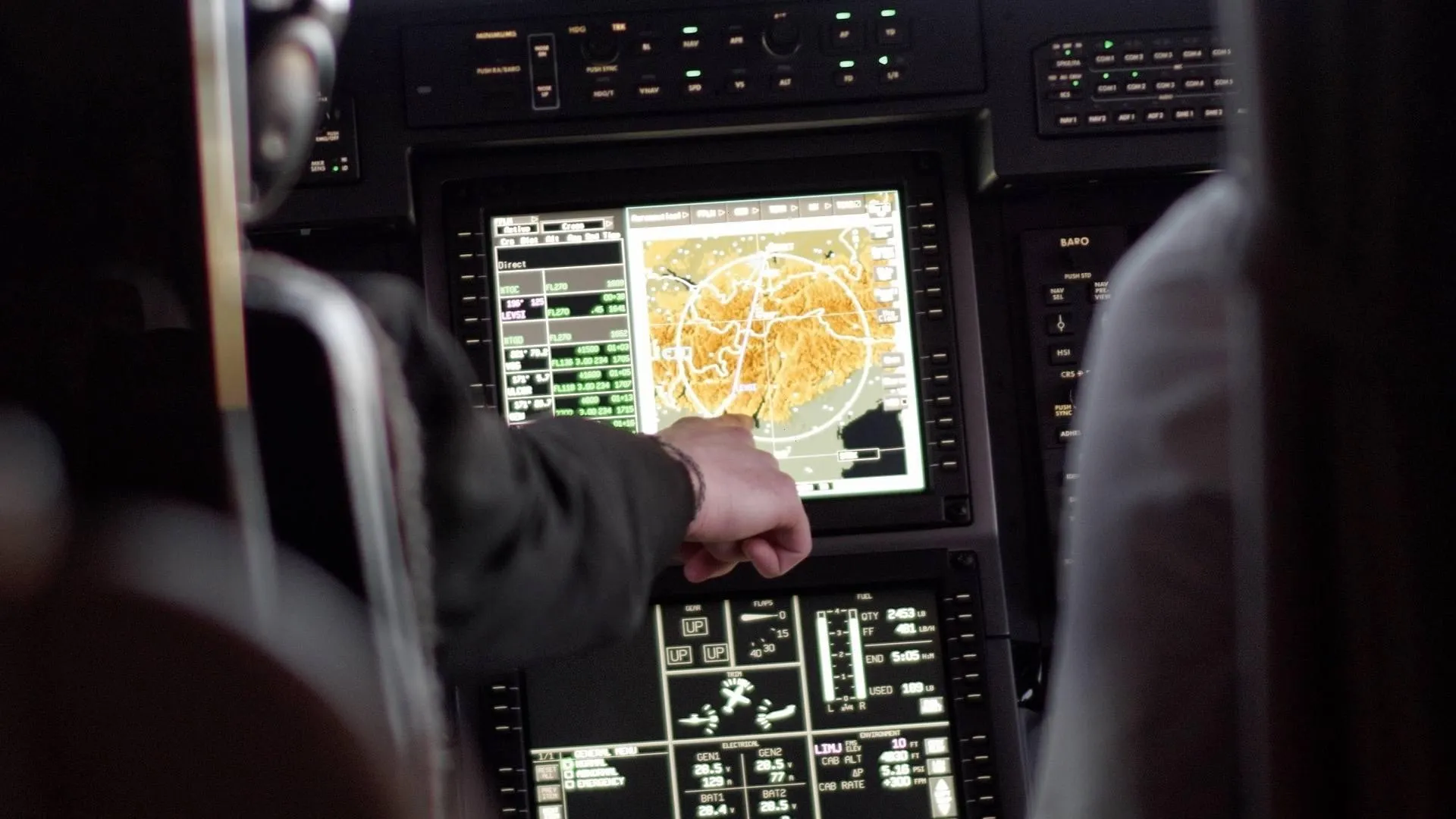 Hand am Navigationsbildschirm im Cockpit