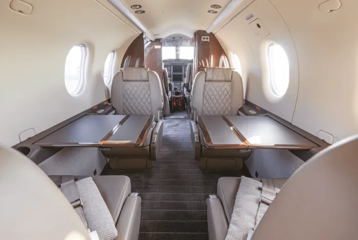 Kabineninnenraum der Pilatus PC-12 NGX mit Ledersitzen und ausgeklappten Tischen, Blick Richtung Cockpit